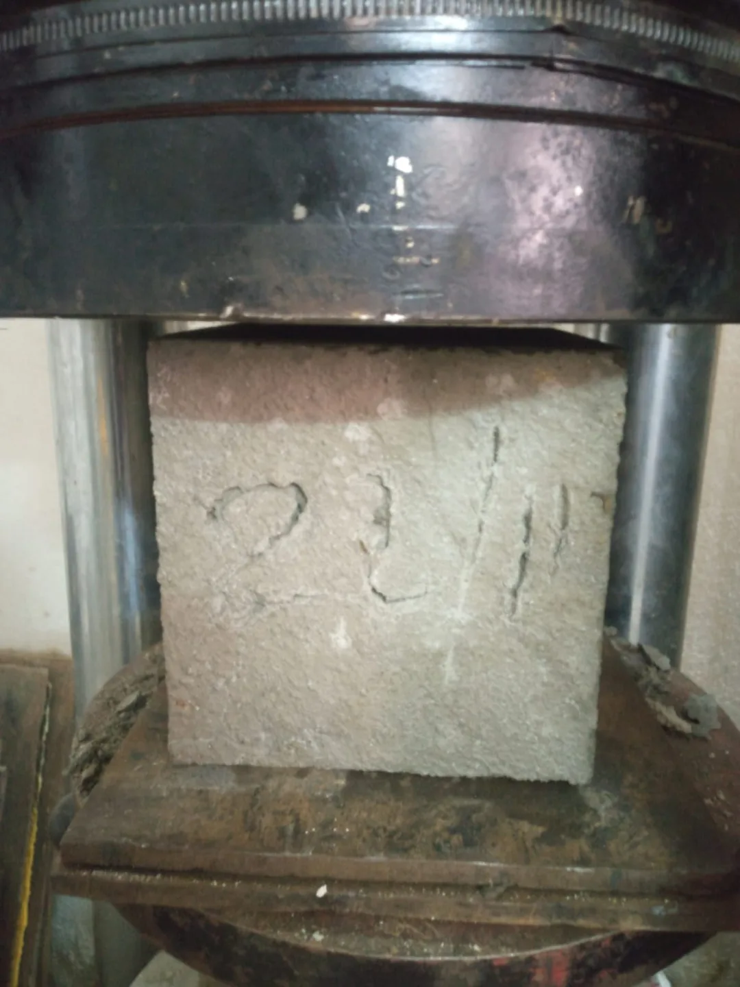 Concrete cube specimen under compression testing in the laboratory